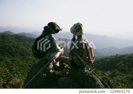 Woman hiker on top of mountain. Hiker with arms up on top of mountain successful young woman enjoying triumph. traveler exploring world. Hikers with backpacks relaxing. Sport and success concept. Woman hiker on top of mountain. Hiker with arms up on top of mountain successful young woman enjoying triumph. traveler exploring world. Hikers with backpacks relaxing. Sport and success concept. 129903270