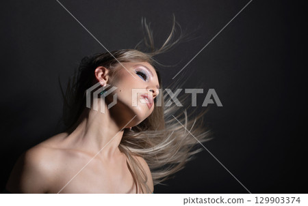 Beautiful woman with flying hair studio portrait 129903374
