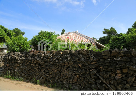 View of a red-tiled roofed house on a coral stone wall on Hatoma Island 129903406