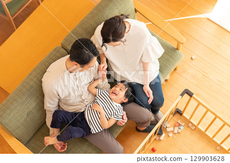 一對年輕夫婦帶著一個孩子在客廳玩耍 129903628