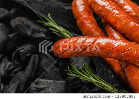 Close-up of grilled sausages with rosemary on charcoal background. top view. copy space Close-up of grilled sausages with rosemary on charcoal background. top view. copy space 129903693