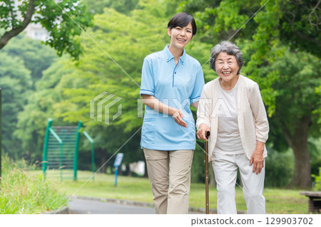 Senior woman and caregiver taking a walk 129903702