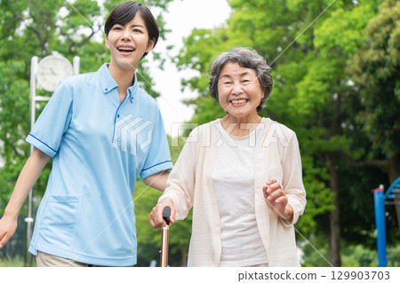 Senior woman and caregiver taking a walk 129903703