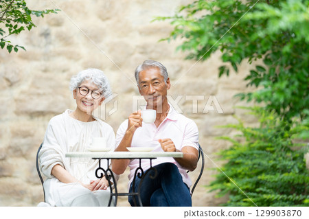 Senior couple sitting on a bench drinking tea 129903870