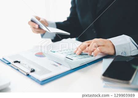 Business hands holding saving account passbook with calculator, account and saving concept. finance effectively, calculate income, track each bill and payment, accounting for bank statements and tax. Business hands holding saving account passbook with calculator, account and saving concept. finance effectively, calculate income, track each bill and payment, accounting for bank statements and tax. 129903989
