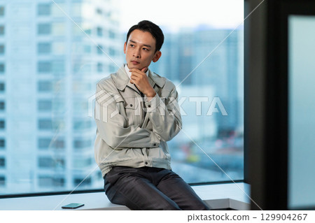 一位身穿工作服的男子一邊看著摩天大樓一邊思考 129904267