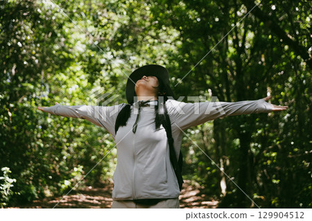 Young female traveler with backpack walking in national park or forest. recreation sport in nature. Female person bag, wave for hiking journey in woods. adventure in forest. trekking with backpack 129904512