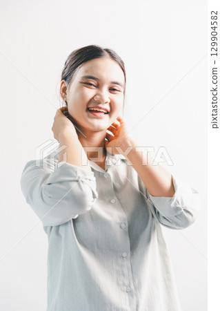 Asian woman rejoicing, looking happy, champion, fist pump gesture, standing over white background. young woman had happy, positive expression on her face, highlighted by bright smile. 129904582