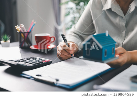 Real estate agent agree to buy home to clients agency office. House model, real estate agent, customer discussing for contract to buy house, insurance, loan real estate background. Concept agreement. 129904589