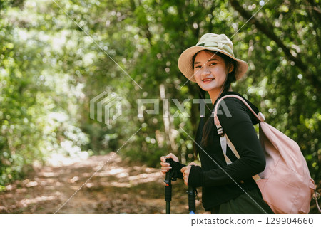 Young female traveler with backpack walking in national park or forest. recreation sport in nature. Female person bag, wave for hiking journey in woods. adventure in forest. trekking with backpack 129904660