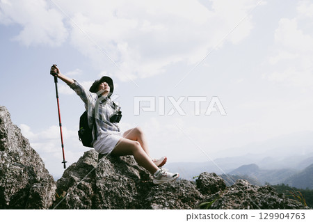 Woman hiker on top of mountain. Hiker with arms up on top of mountain successful young woman enjoying triumph. traveler exploring world. Hikers with backpacks relaxing. Sport and success concept. Woman hiker on top of mountain. Hiker with arms up on top of mountain successful young woman enjoying triumph. traveler exploring world. Hikers with backpacks relaxing. Sport and success concept. 129904763