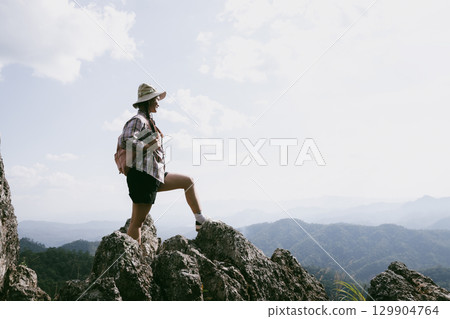 Woman hiker on top of mountain. Hiker with arms up on top of mountain successful young woman enjoying triumph. traveler exploring world. Hikers with backpacks relaxing. Sport and success concept. Woman hiker on top of mountain. Hiker with arms up on top of mountain successful young woman enjoying triumph. traveler exploring world. Hikers with backpacks relaxing. Sport and success concept. 129904764