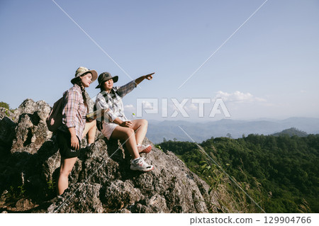 Woman hiker on top of mountain. Hiker with arms up on top of mountain successful young woman enjoying triumph. traveler exploring world. Hikers with backpacks relaxing. Sport and success concept. 129904766
