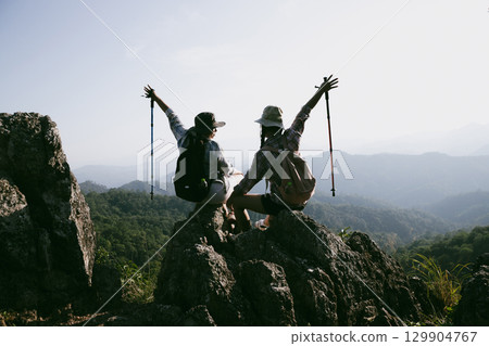 Woman hiker on top of mountain. Hiker with arms up on top of mountain successful young woman enjoying triumph. traveler exploring world. Hikers with backpacks relaxing. Sport and success concept. 129904767