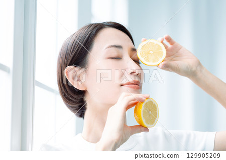 A transparent woman holding lemons in both hands in the light. Close-up of the face. A transparent woman holding lemons in both hands in the light. Close-up of the face. 129905209