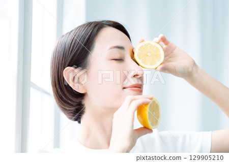A transparent woman holding lemons in both hands in the light. Close-up of the face. A transparent woman holding lemons in both hands in the light. Close-up of the face. 129905210