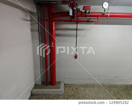 Red Pipes and Equipment in Underground Parking Garage Environment Red Pipes and Equipment in Underground Parking Garage Environment 129905282