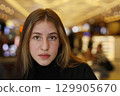 A girl sitting in a crowded cafe. 129905670