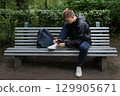 A teenage boy ties his shoelaces. 129905671