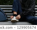 boy on a bench tying his shoelaces. 129905674