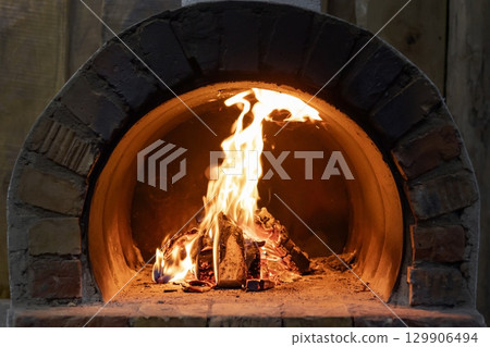wood burning brick oven for outdoor cooking with logs burning inside. wood burning brick oven for outdoor cooking with logs burning inside. 129906494