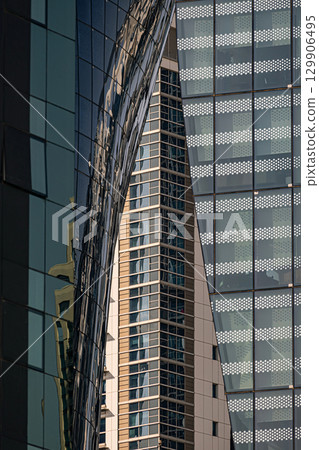 Different glass walls of buildings located close to each other. Architecture details, exterior. Abstract futuristic background Different glass walls of buildings located close to each other. Architecture details, exterior. Abstract futuristic background 129906495