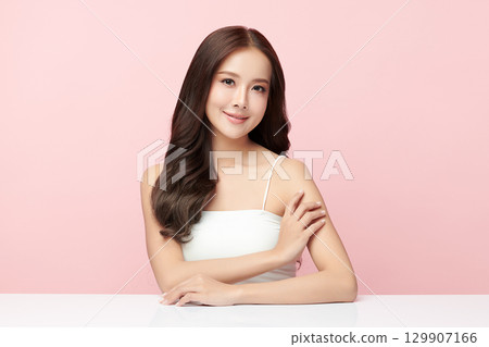 A beautiful young Asian woman with clean, fresh skin against a pink background. Skincare, facial treatment, cosmetology, beauty, and spa. An elegant portrait of an Asian woman. 129907166