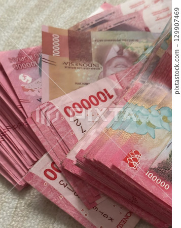 Abundant Pile of Pink 100000 Indonesian Rupiah Banknotes on a Textured Surface. Abundant Pile of Pink 100000 Indonesian Rupiah Banknotes on a Textured Surface. 129907469