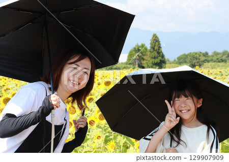 Mother and daughter holding a parasol in a field of hiwamari 129907909