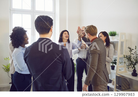 Happy colleagues giving high five at meeting at office, celebrating success or business achievement Happy colleagues giving high five at meeting at office, celebrating success or business achievement 129907983