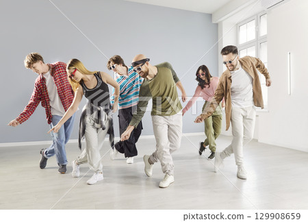 Joyful young adults in casual wear dancing together in studio and enjoying modern hip hop session. 129908659