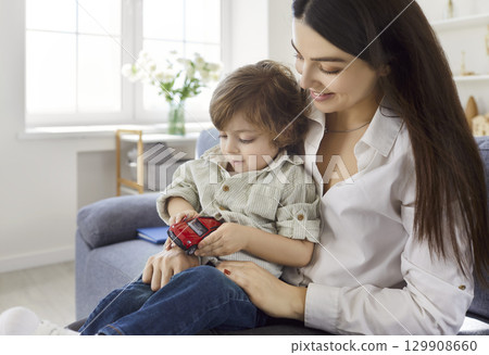 Mother, young babysitter and little child playing with toy car, having amusing game together, caring 129908660