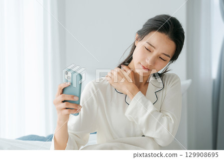 一位女士醒來後正在看她的智慧型手機 一位女士醒來後正在看她的智慧型手機 129908695