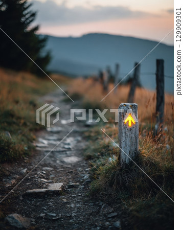 Trail Marker Guiding Hikers Through Scenic Mountain Path at Dusk With Golden Light Illuminating the Landscape 129909301