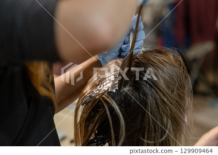 Hair coloring process demonstrating skillful application in a salon environment during daylight hours Hair coloring process demonstrating skillful application in a salon environment during daylight hours 129909464