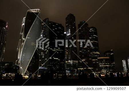 City skyline showcasing modern architecture at night with illuminated buildings and clouded sky 129909507