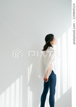 Woman in denim standing by the window (vertical) 129909524