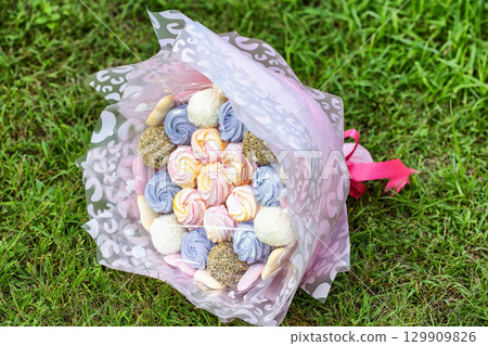 Multicolored gift set of marshmallow sweets in a bouquet on green grass, close-up Multicolored gift set of marshmallow sweets in a bouquet on green grass, close-up 129909826