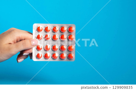 Blister with red pills in hand on blue background. Concept of chondroprotector pills for joint health. Copy space for text, painkillers 129909835