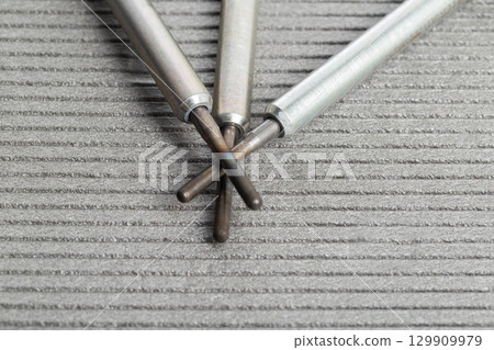 Modern rod ceramic glow plugs for easier starting of a diesel engine in cold weather on a gray background. Automotive spare part, heating element. Modern rod ceramic glow plugs for easier starting of a diesel engine in cold weather on a gray background. Automotive spare part, heating element. 129909979