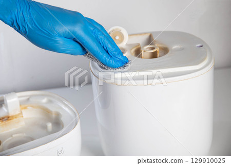 Wiping and cleaning scale and rust from a chemical agent in a humidifier. Hand in a blue glove. Maintenance of humidifiers, industry 129910025