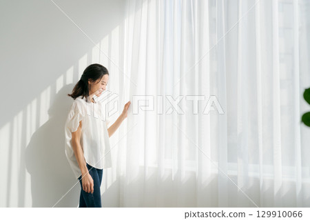 一位身穿牛仔服的女士站在窗邊 129910066