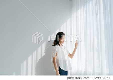 一位身穿牛仔服的女士站在窗邊 129910067