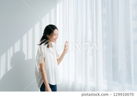A woman in denim standing by the window 129910070