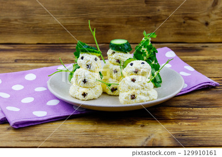 Christmas salad in the shape of snowmen and Christmas tree on a plate on wooden table Christmas salad in the shape of snowmen and Christmas tree on a plate on wooden table 129910161