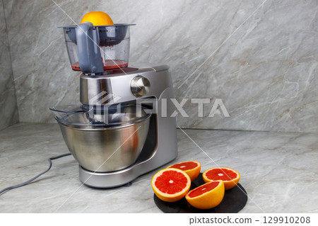 Modern electric juicer and grapefruits on a kitchen table. Preparing fresh squeezed grapefruit juice 129910208