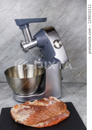 Electric eat grinder and fresh meat on kitchen table. Preparation of minced meat Electric eat grinder and fresh meat on kitchen table. Preparation of minced meat 129910211