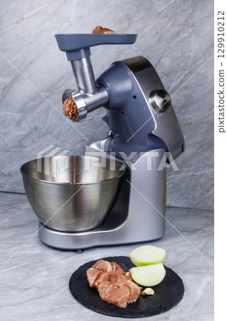 Electric eat grinder and fresh meat on kitchen table. Preparation of minced meat Electric eat grinder and fresh meat on kitchen table. Preparation of minced meat 129910212