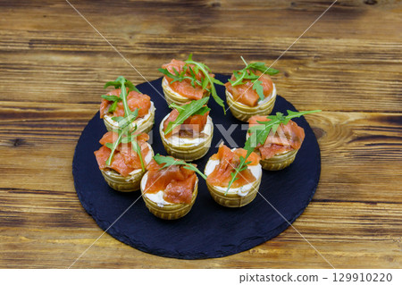 Tartlets with salmon, cream cheese and arugula on  wooden table 129910220
