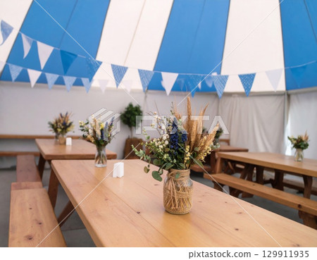 Interior with Wooden Tables and Floral Centerpieces Under Blue and White Bunting 129911935